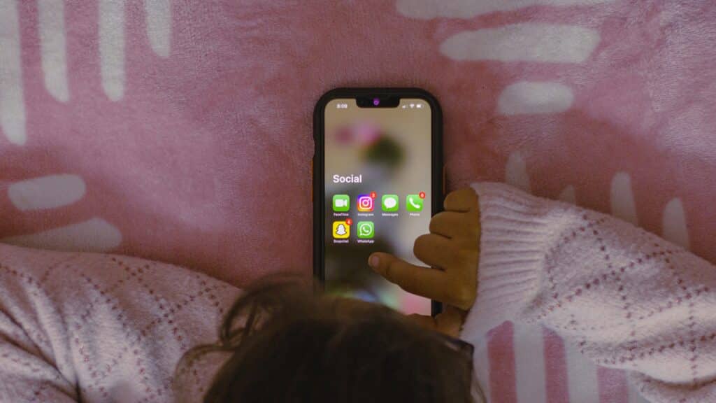 child hands holding phone with social media apps