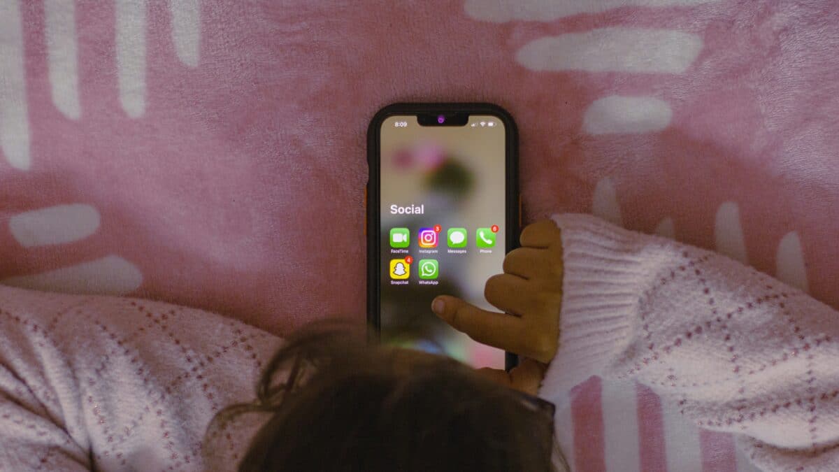 child hands holding phone with social media apps